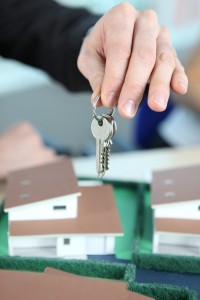 Image of a hand holding doorkeys over a model house
